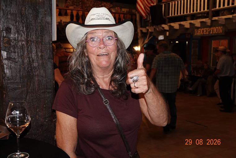 Bezoekster met witte cowboyhoed die haar duim omhoog steekt